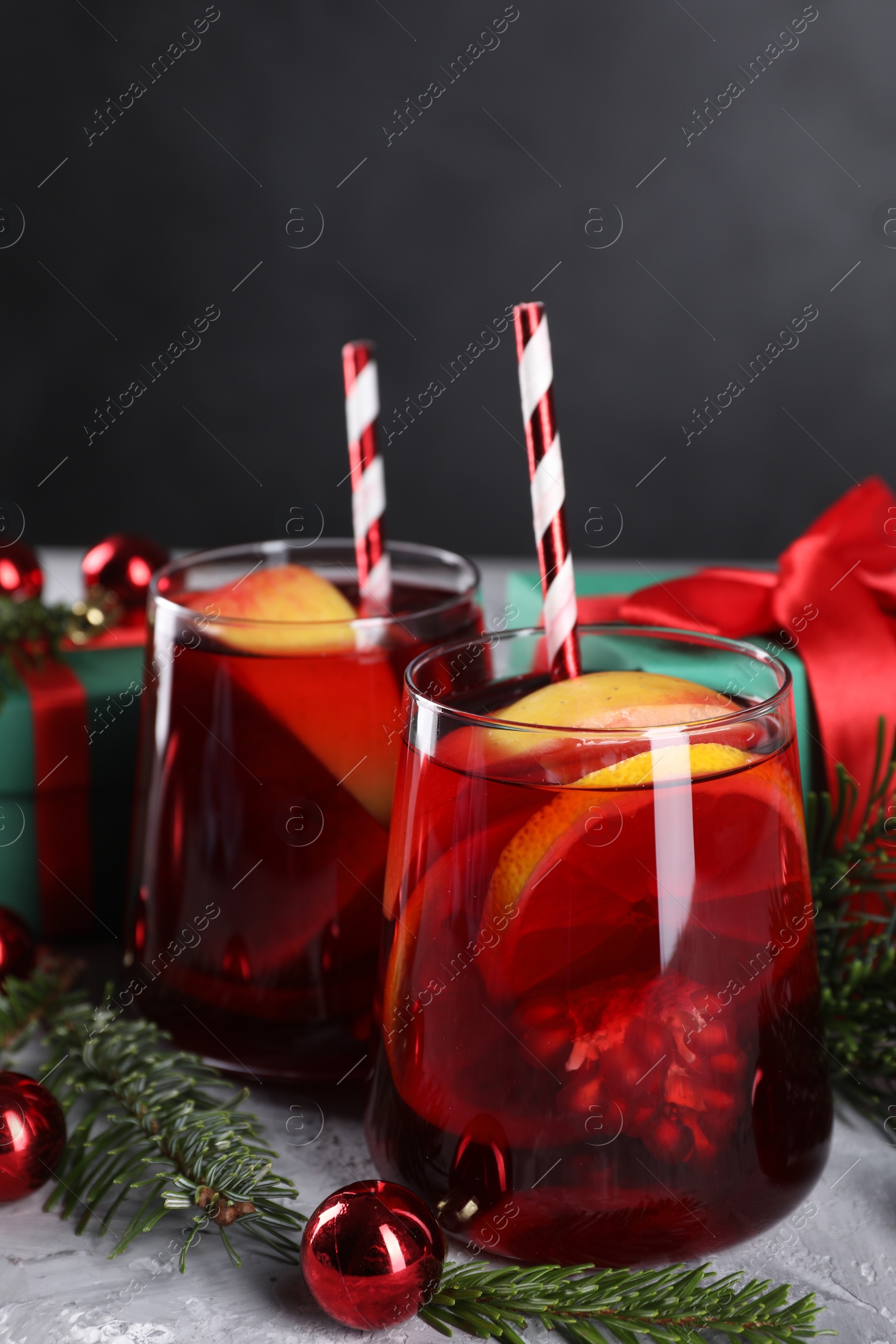 Photo of Delicious Sangria drink in glasses and Christmas decorations on grey table, closeup