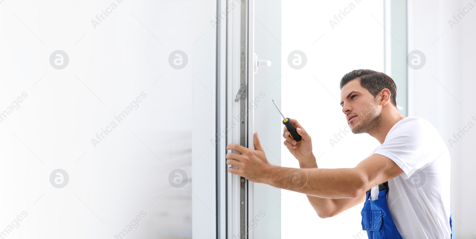 Image of Construction worker repairing plastic window with screwdriver indoors, space for text. Banner design