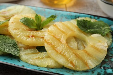 Photo of Tasty grilled pineapple slices and mint on plate, closeup