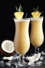 Photo of Tasty Pina Colada cocktails on dark table