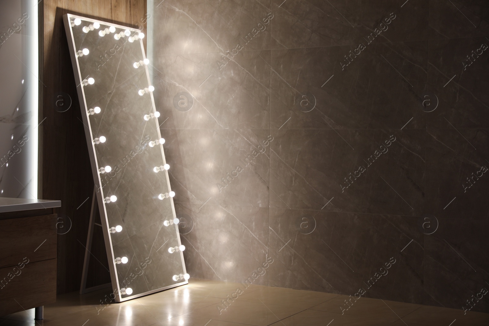 Photo of Modern mirror with light bulbs near wooden wall in room. Space for text