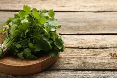 Photo of Bunch of fresh coriander on wooden table, space for text