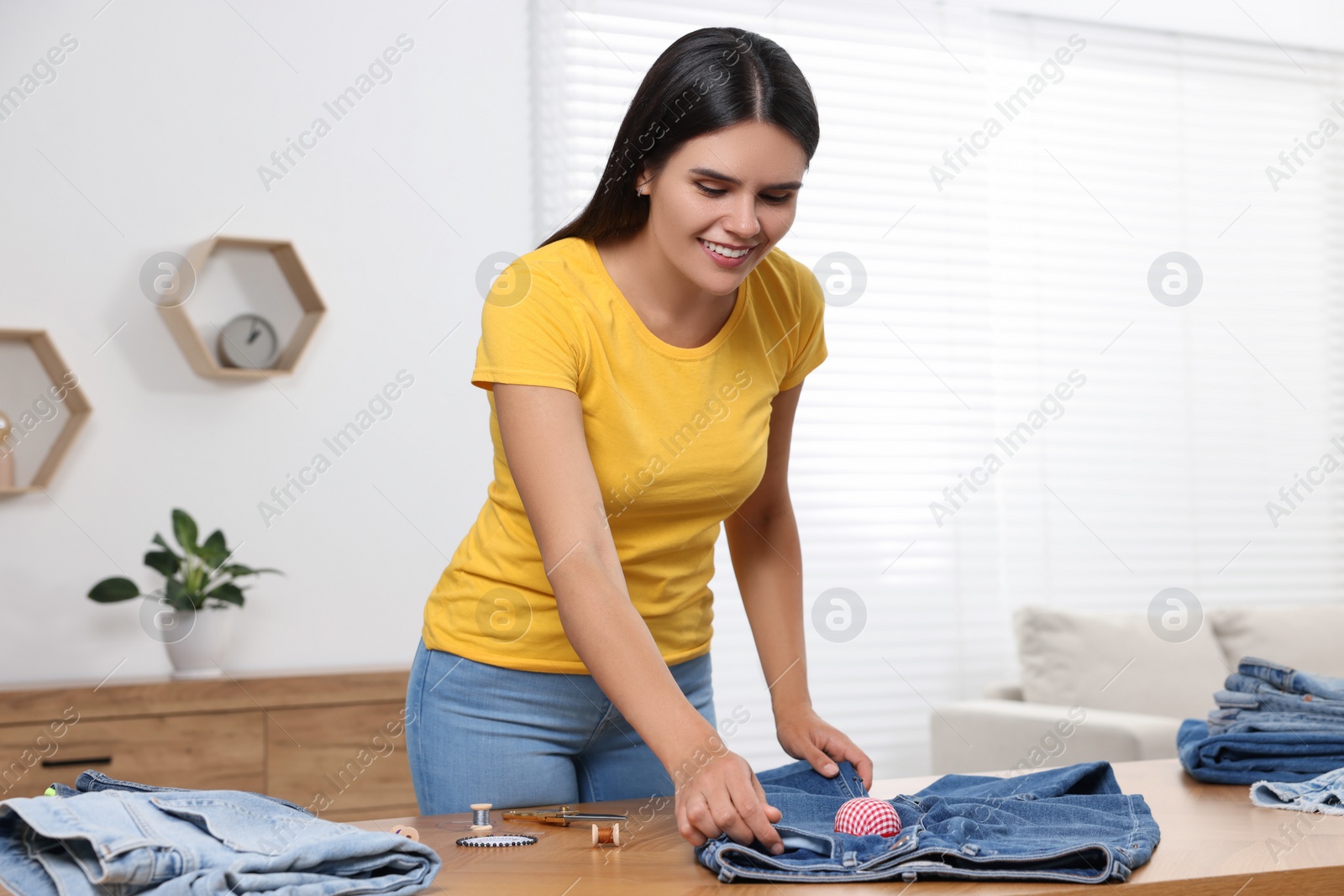 Photo of Young woman with jeans at wooden table indoors