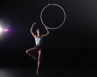 Photo of Young woman performing acrobatic element on aerial ring indoors. Space for text