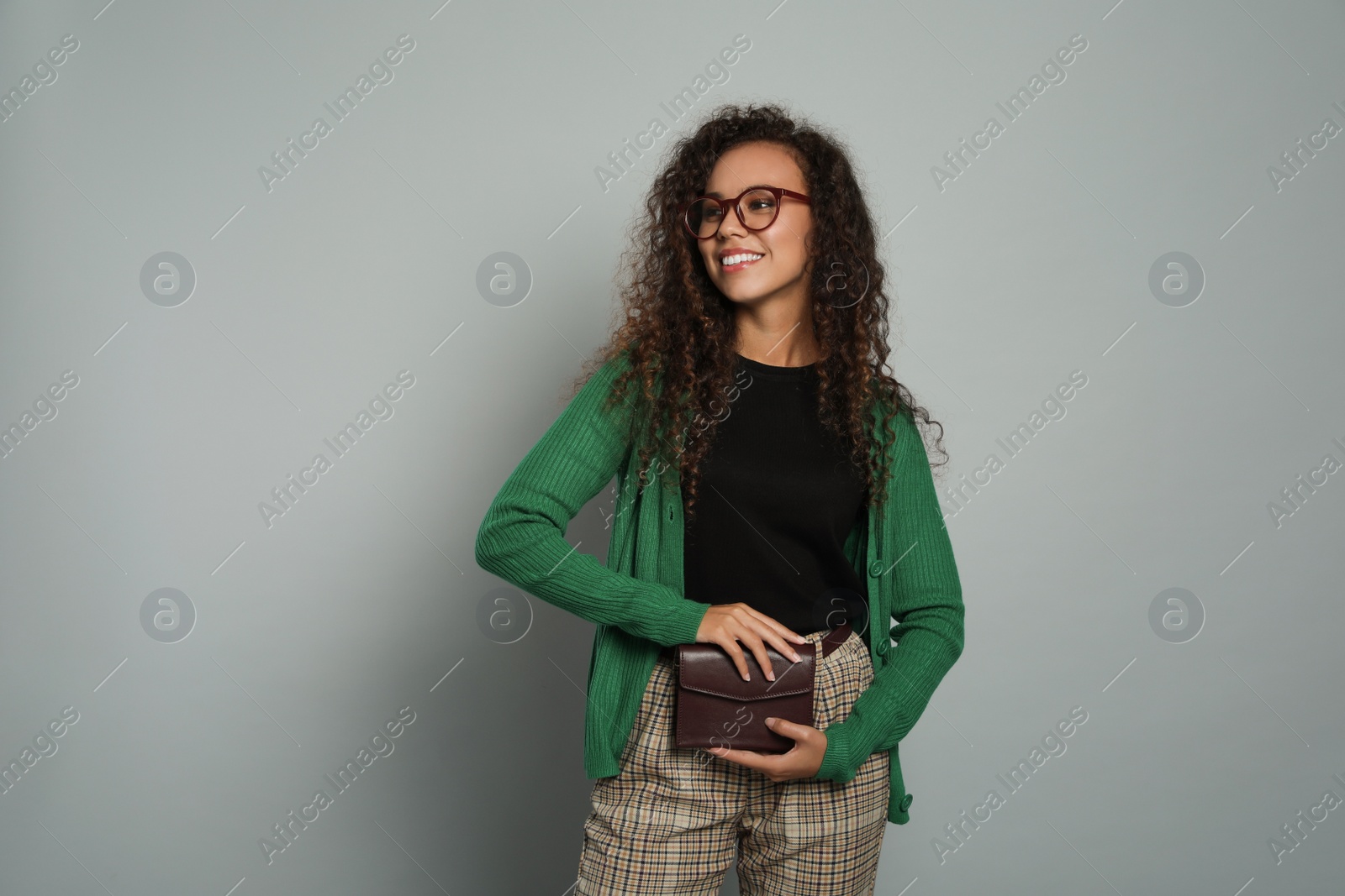 Photo of Beautiful African American woman with stylish waist bag on grey background