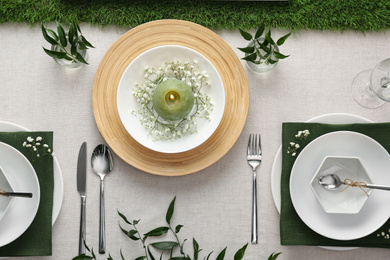 Elegant table setting with green plants on light cloth, flat lay