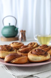 Photo of Many tasty cinnamon rolls on white table, closeup. Space for text