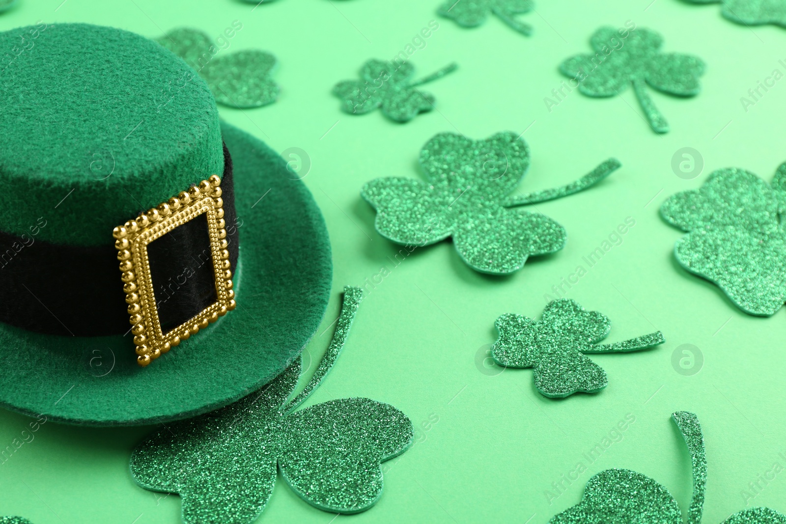 Photo of St. Patrick's day. Leprechaun hat and decorative clover leaves on green background