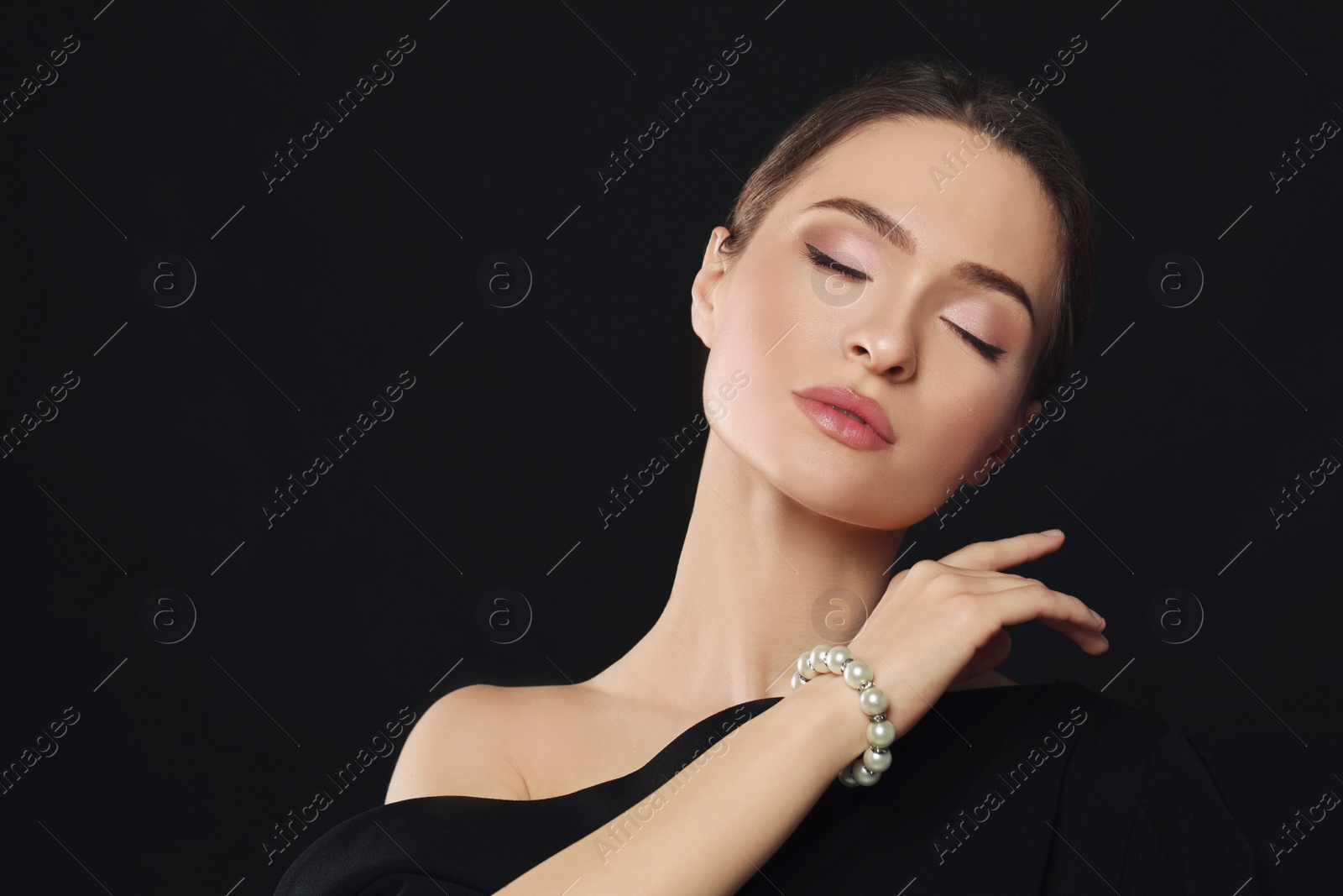 Photo of Young woman wearing elegant pearl bracelet on black background, space for text