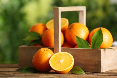 Photo of Fresh ripe oranges on wooden table against blurred background