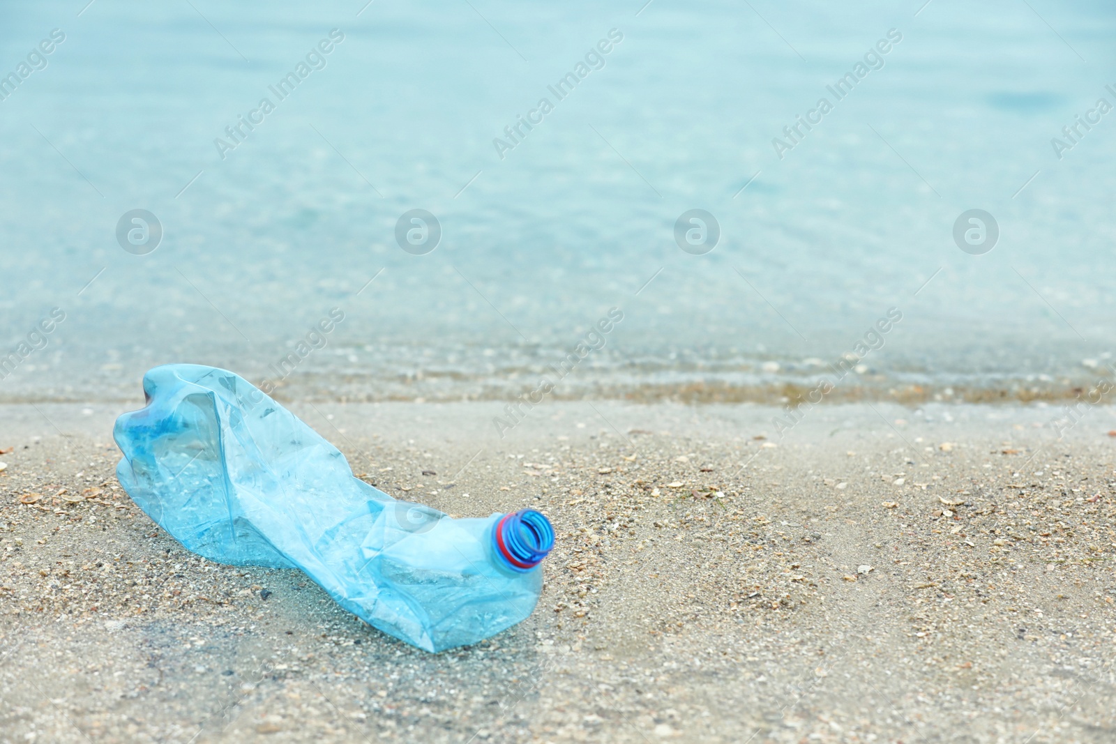 Photo of Used plastic bottle on beach, space for text. Recycling problem