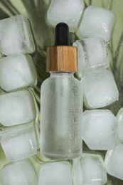 Bottle of cosmetic product and ice cubes on glass surface, flat lay