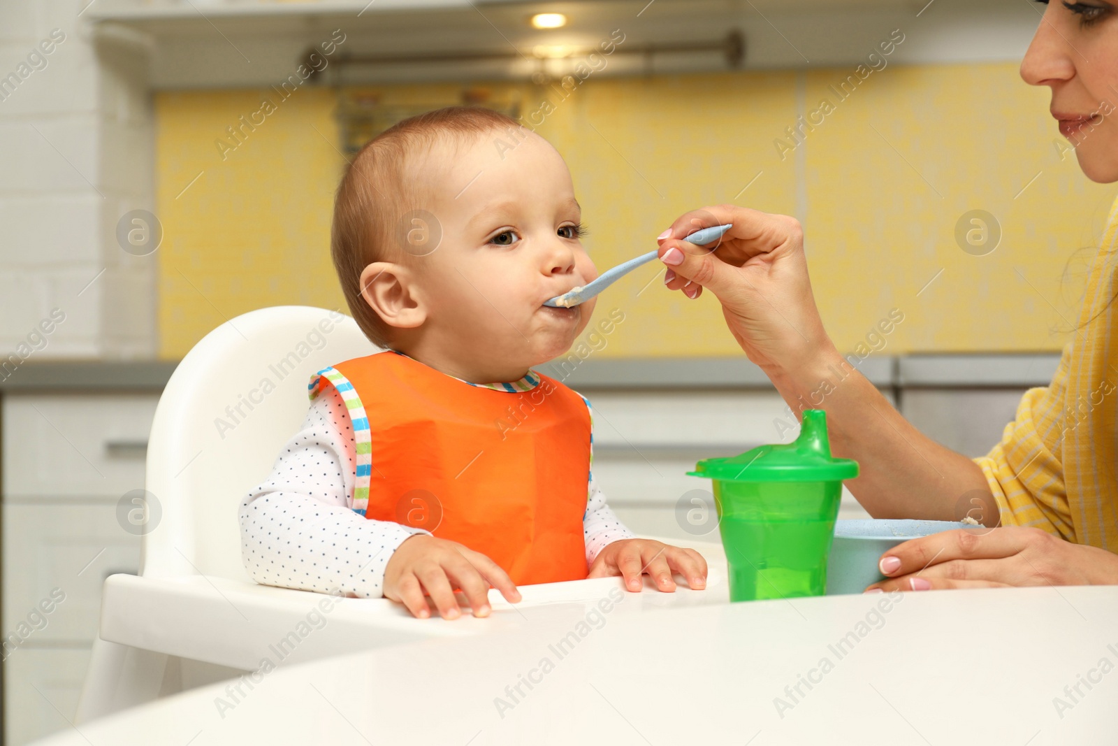 Photo of Young mother feeding her little baby at home