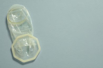 Unrolled female condom on light blue background, top view and space for text. Safe sex