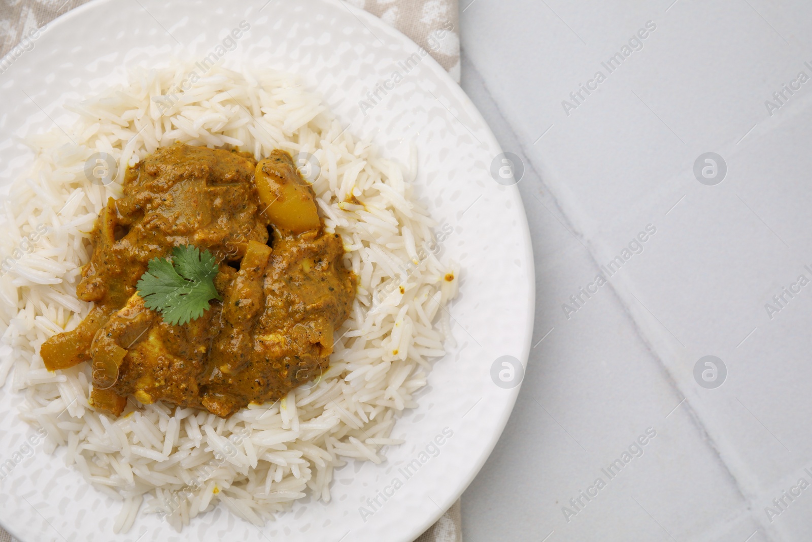 Photo of Delicious chicken curry with rice on white tiled table, top view