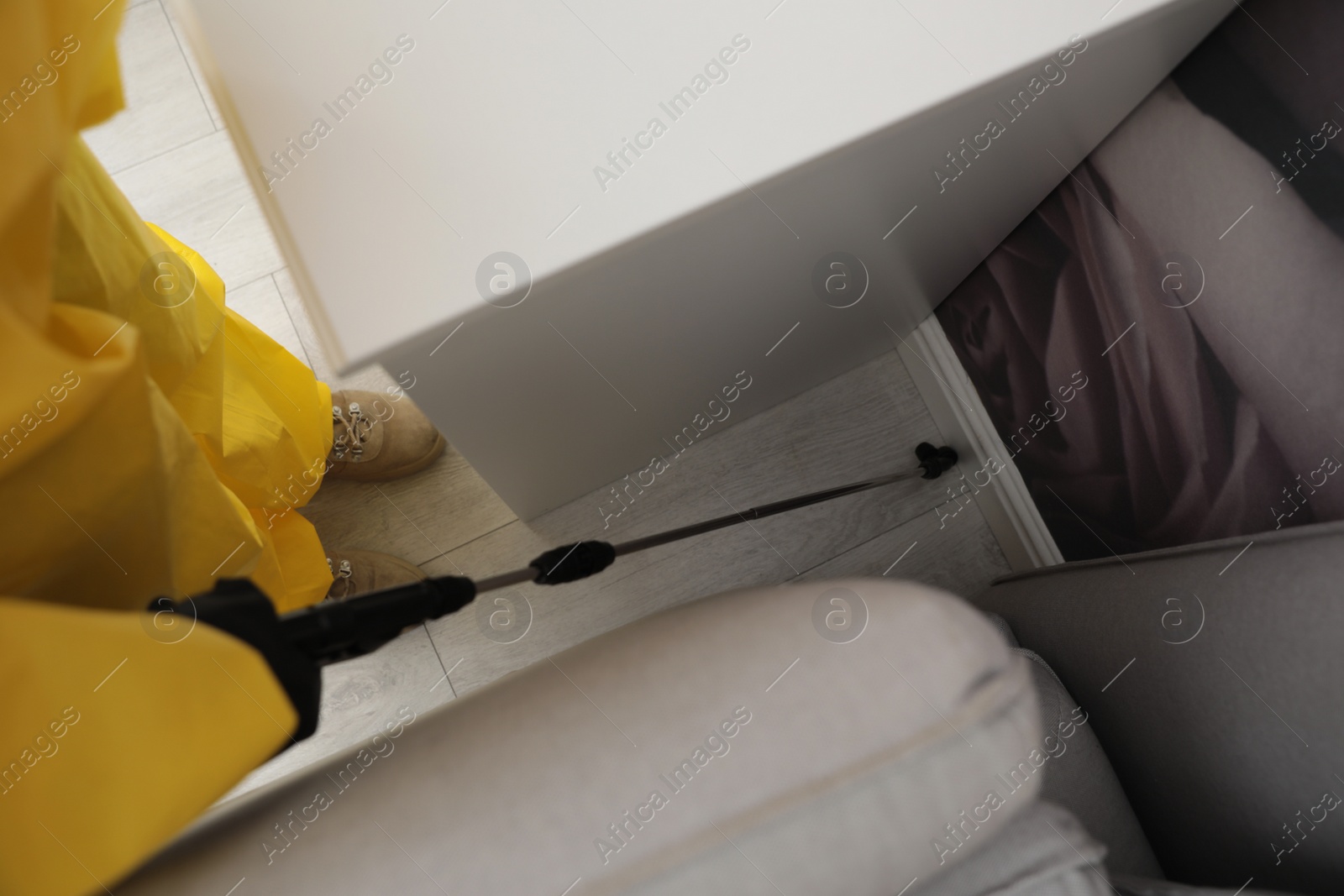 Photo of Pest control worker spraying pesticide on floor indoors, top view