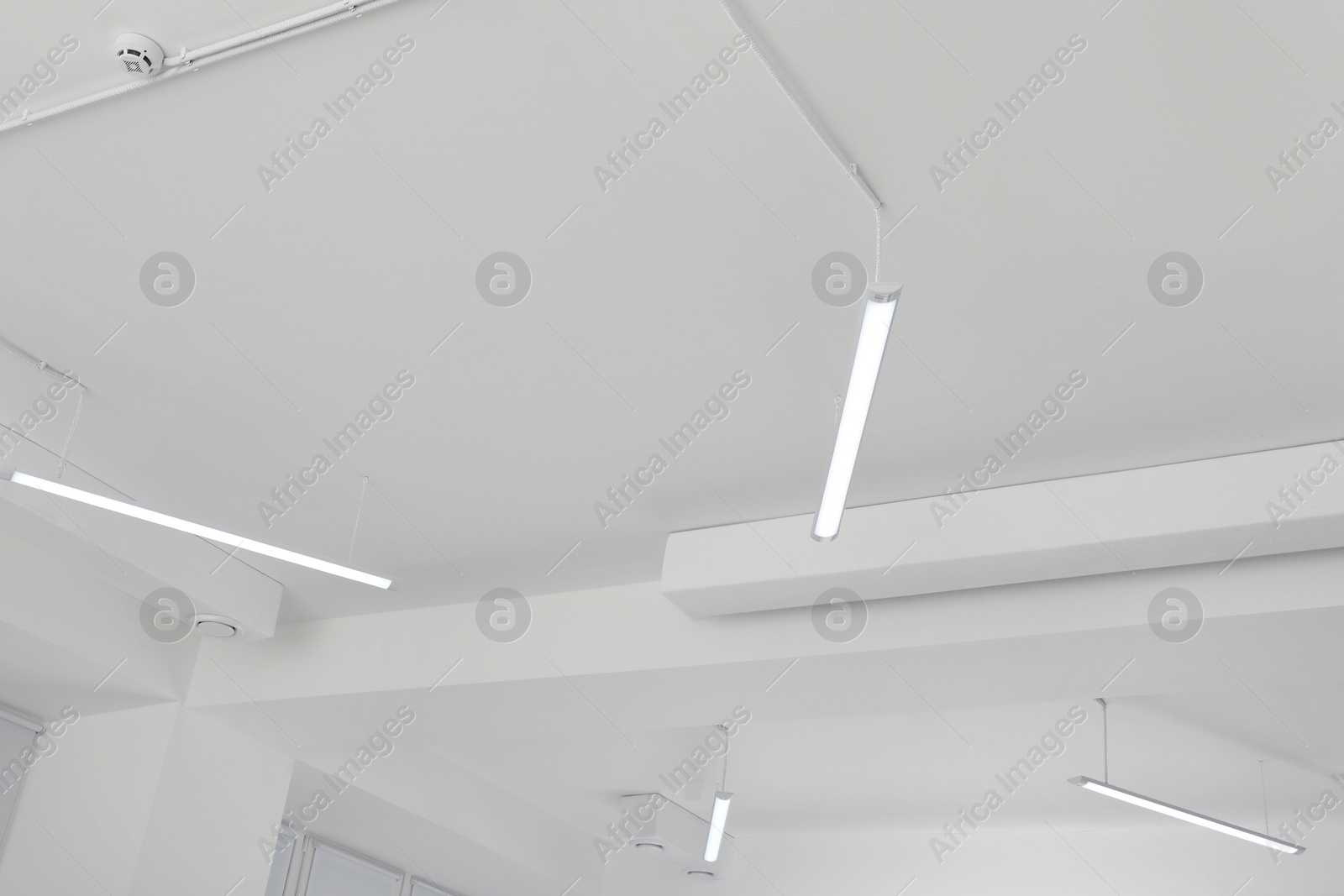 Photo of White ceiling with modern lighting in room, low angle view