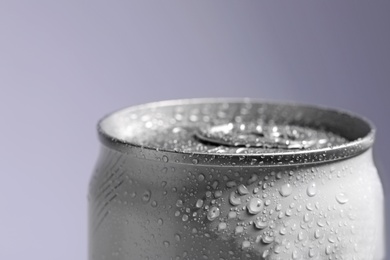 Aluminum can of beverage covered with water drops on grey background, closeup. Space for text