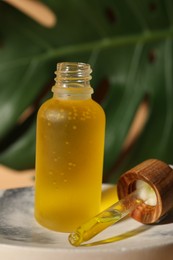 Photo of Bottle of face serum on soap dish against beige background, closeup