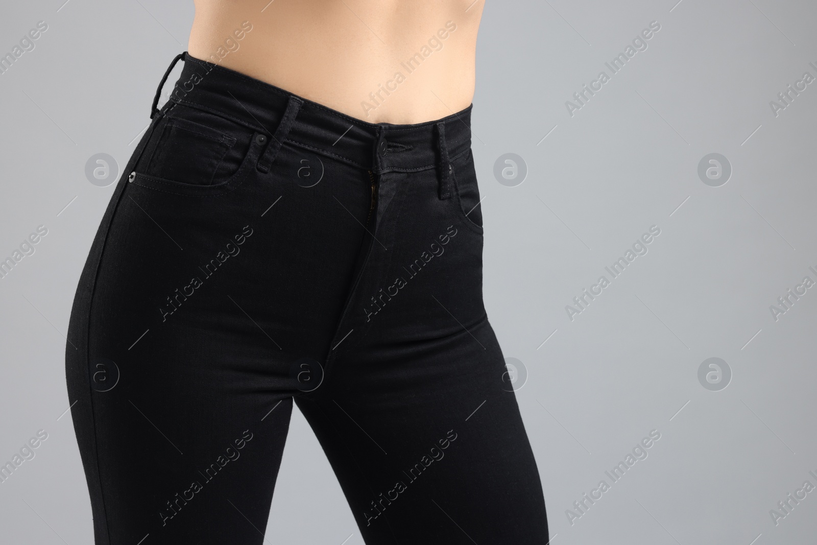 Photo of Woman wearing stylish black jeans on light gray background, closeup. Space for text