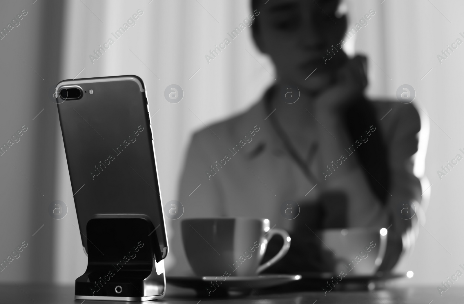 Photo of Lonely woman looking at smartphone on foreground, space for text. Black and white effect