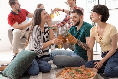 Young people having fun party with delicious pizza indoors