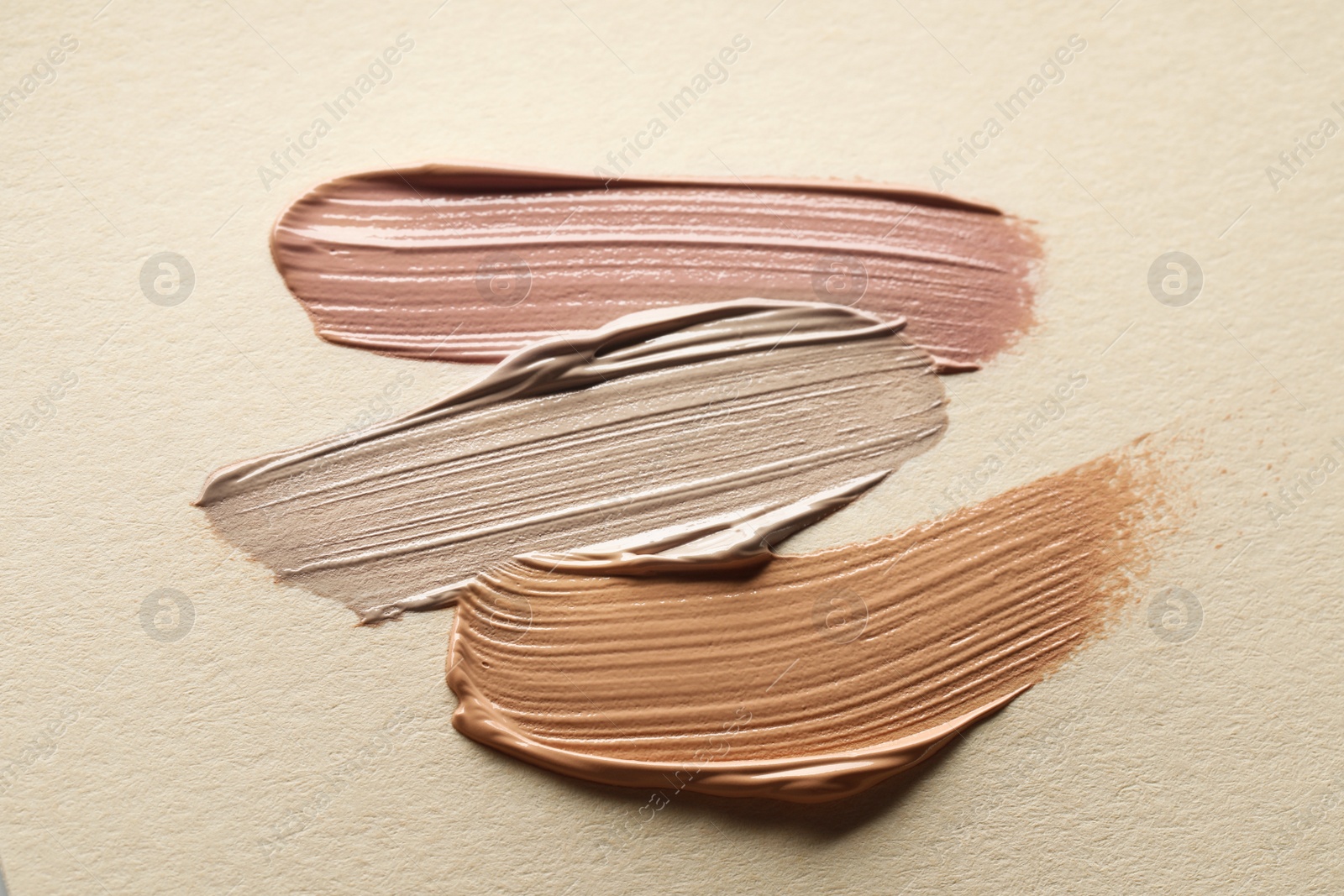 Image of Different shades of liquid foundation on beige background, top view