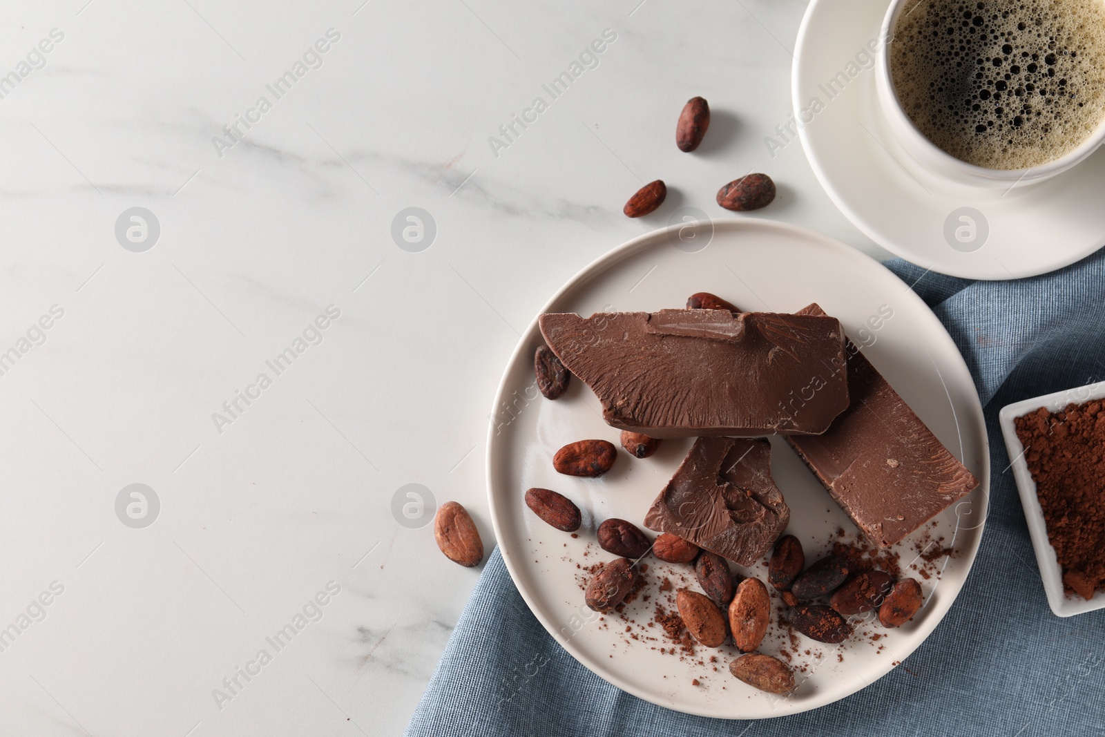 Photo of Pieces of tasty milk chocolate, cocoa beans and coffee on white marble table, flat lay. Space for text