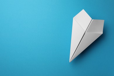 Photo of Handmade white paper plane on light blue background, top view. Space for text
