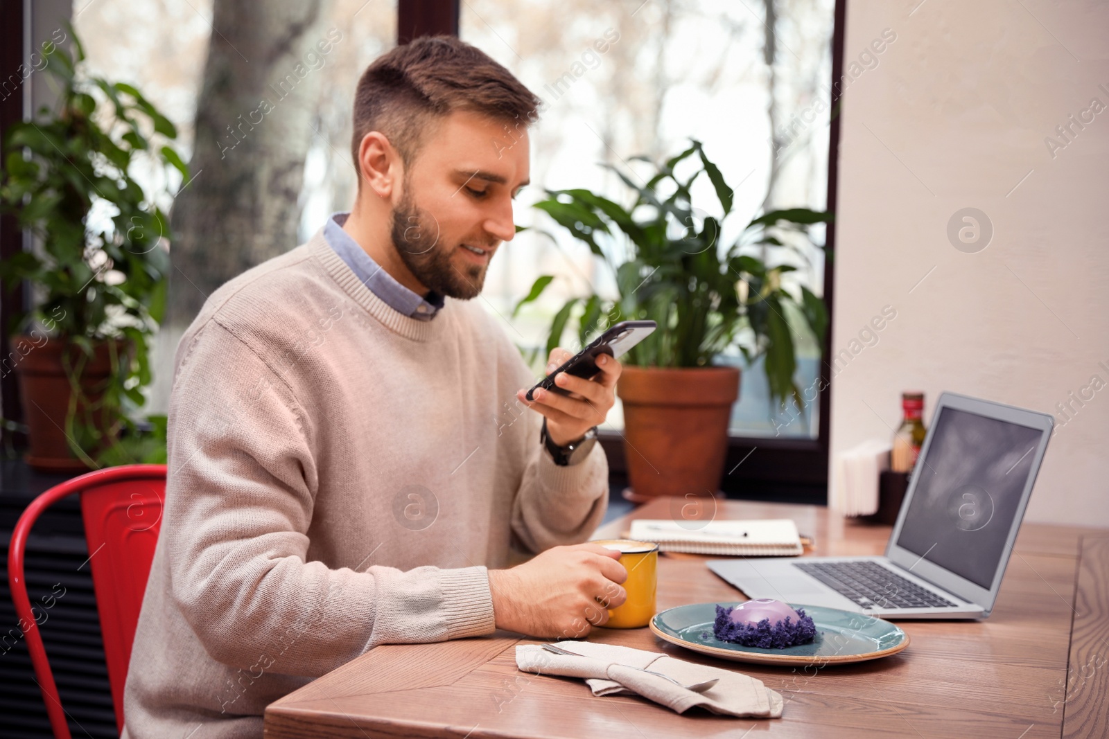 Photo of Male blogger taking photo of dessert and coffee at table in cafe