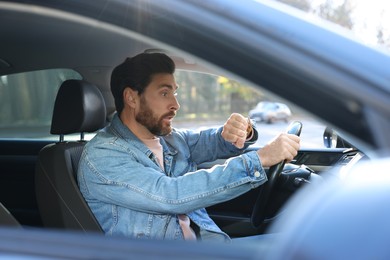 Photo of Emotional man checking time on watch in car. Being late concept