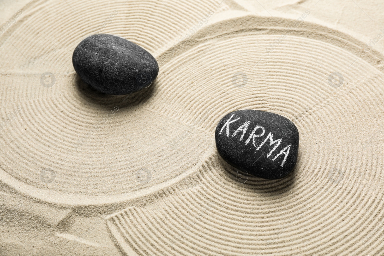 Photo of Stones with word Karma on sand, above view