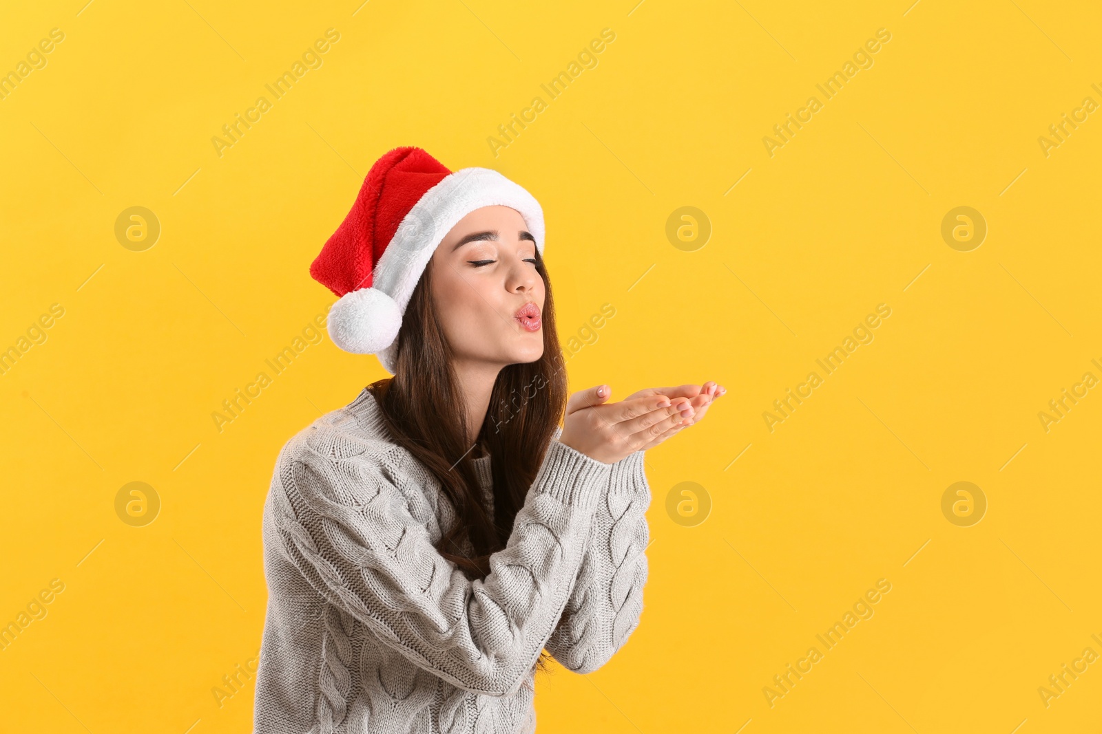 Photo of Beautiful woman wearing Santa Claus hat on yellow background