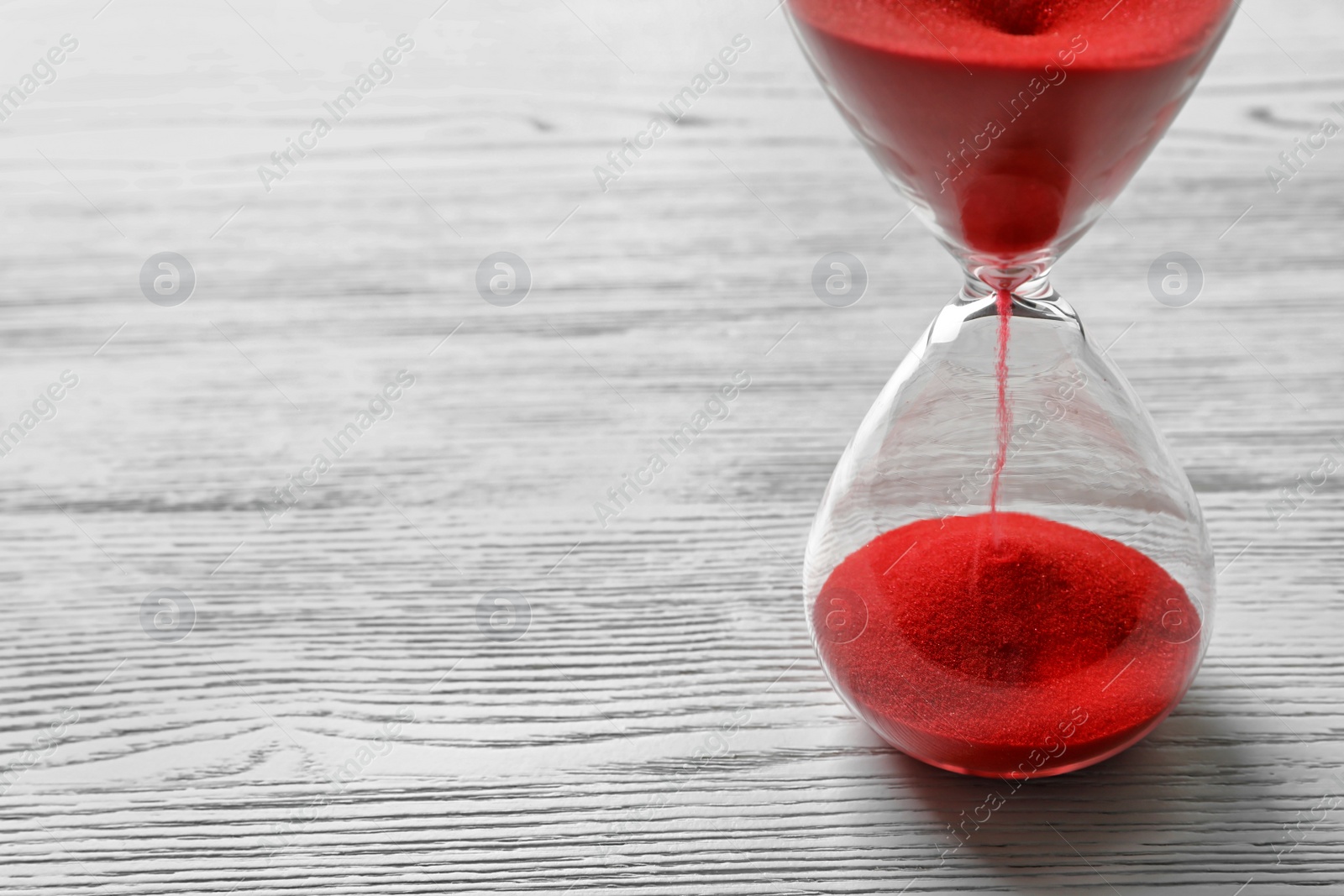 Photo of Hourglass with flowing red sand on wooden background. Time management