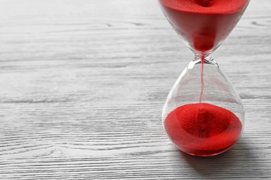 Photo of Hourglass with flowing red sand on wooden background. Time management