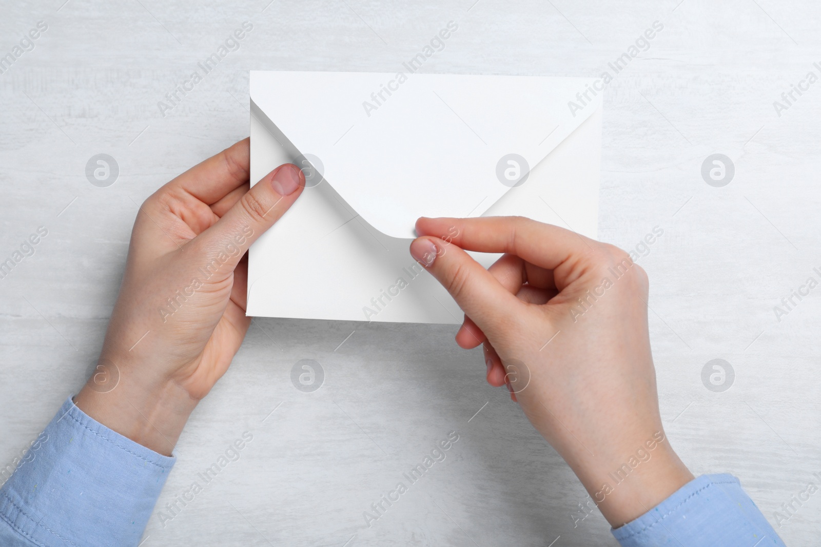 Photo of Woman with envelope at light table, top view