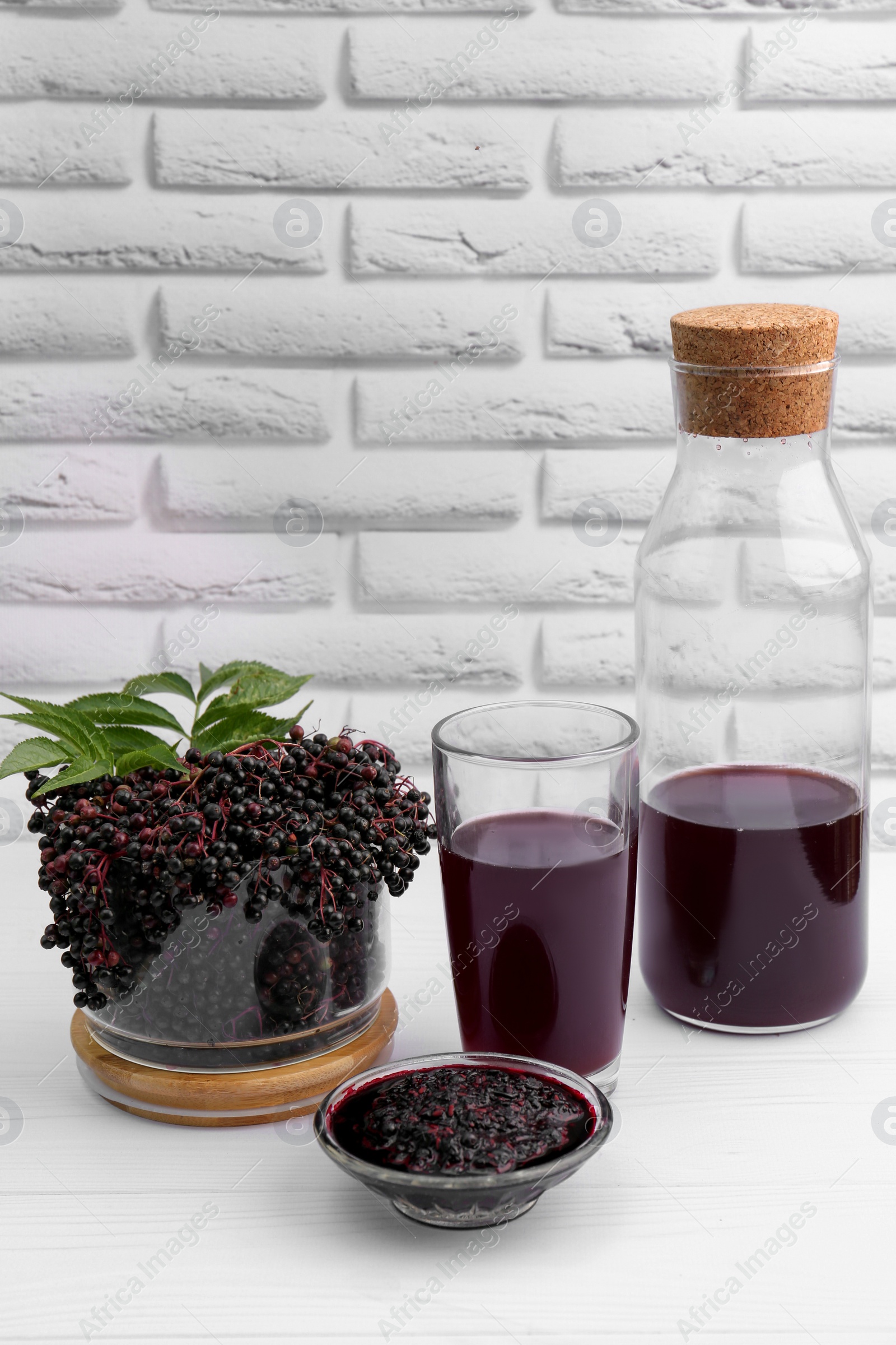 Photo of Elderberry drink and jam with Sambucus berries on white wooden table, space for text