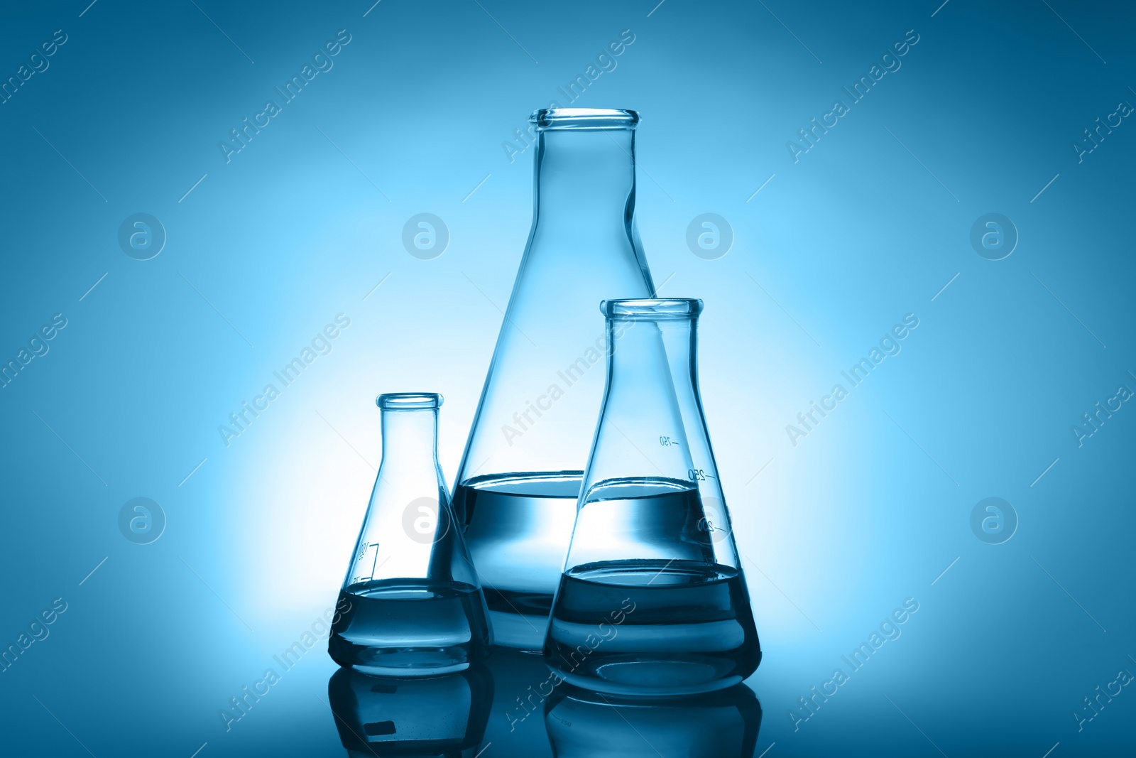 Photo of Conical flasks with liquid on table against color background. Laboratory analysis