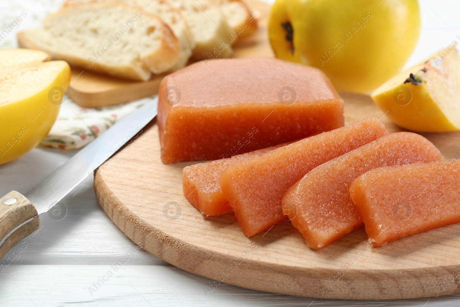 Photo of Tasty sweet quince paste, fresh fruits and knife on white wooden table, closeup