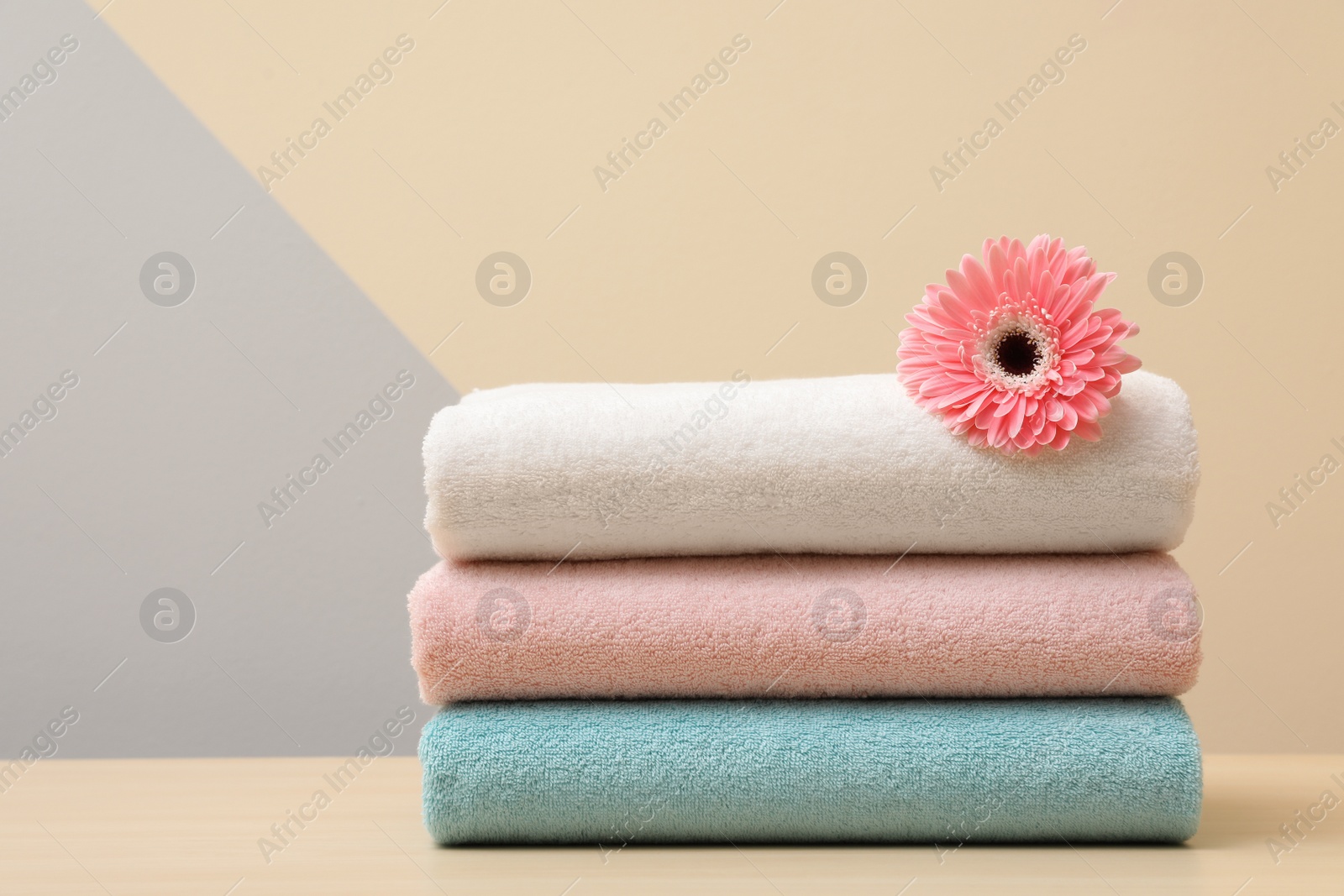Photo of Stack of fresh towels with flower on table. Space for text