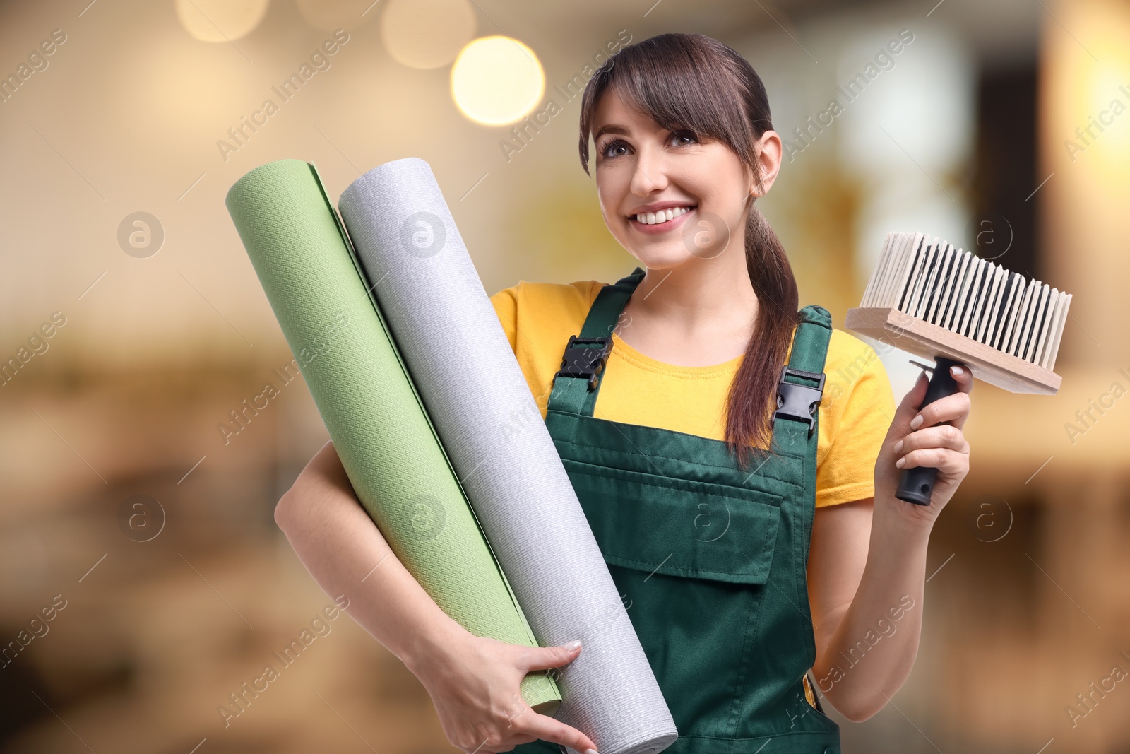 Image of Woman with wallpaper rolls and brush on blurred background