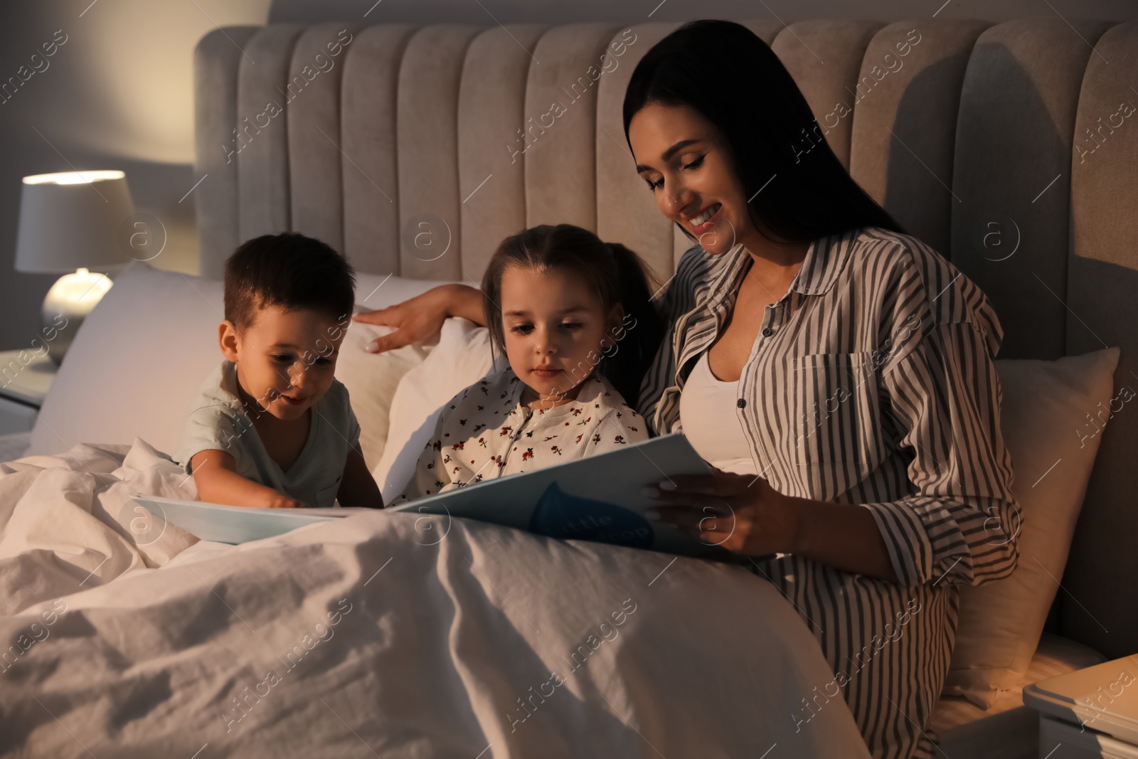 Photo of Mother reading bedtime story to her children at home