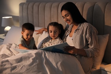 Mother reading bedtime story to her children at home