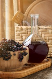 Photo of Elderberry wine and bowl with Sambucus berries on wooden table