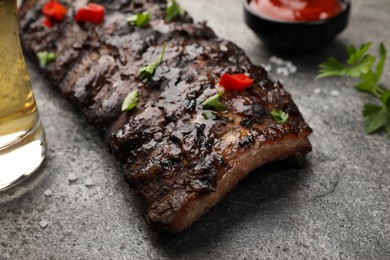 Photo of Tasty grilled ribs and sauce on grey table, closeup