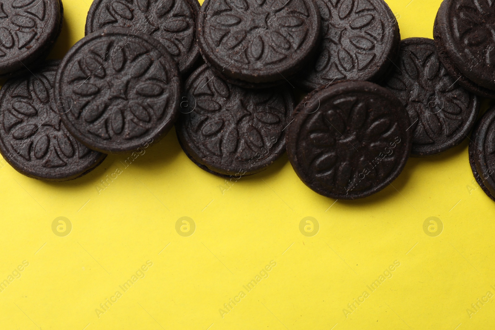 Photo of Tasty sweet sandwich cookies on yellow background, flat lay. Space for text