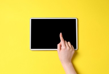 Photo of Online store. Woman using tablet on yellow background, top view