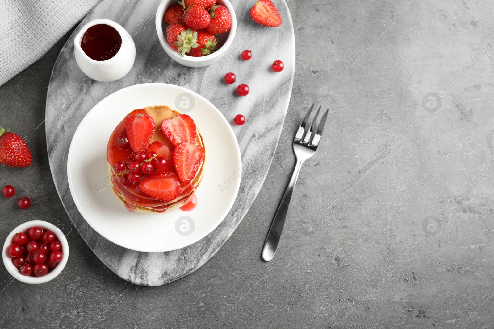 Photo of Tasty pancakes with berries served on grey table, flat lay. Space for text
