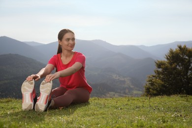 Photo of Young woman doing morning exercise in mountains, space for text