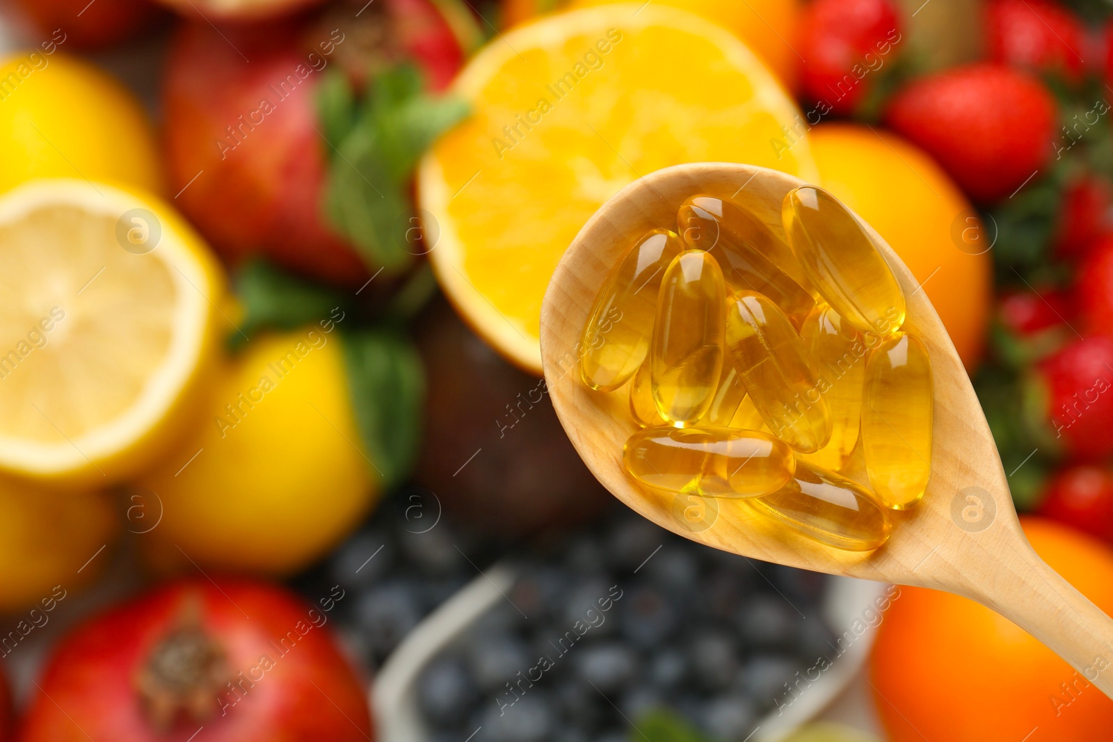 Photo of Vitamin pills in spoon over fresh fruits, top view. Space for text